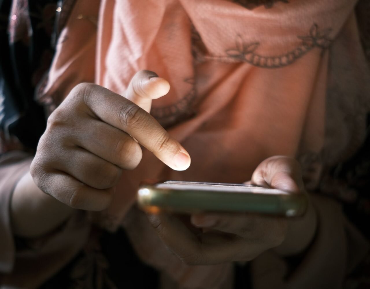 Mãos tocando a tela do celular para conferir saldo, aposta e ganho em um jogo