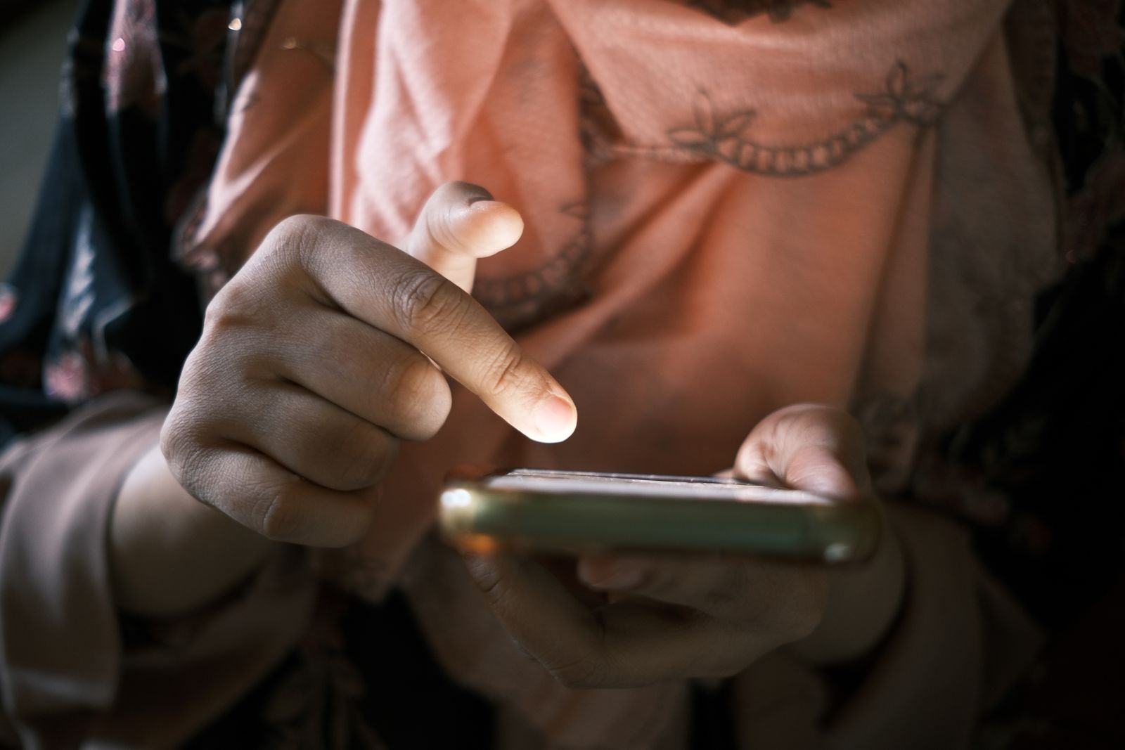 Mãos tocando a tela do celular para conferir saldo, aposta e ganho em um jogo